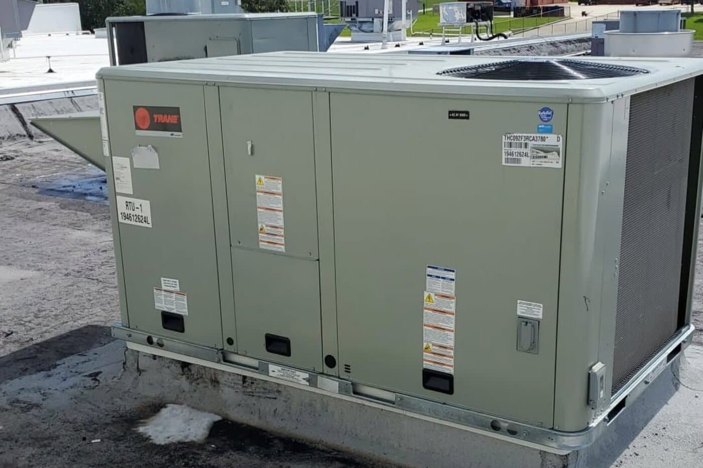 A package air conditioning unit standing on the flat roof of a commercial building.